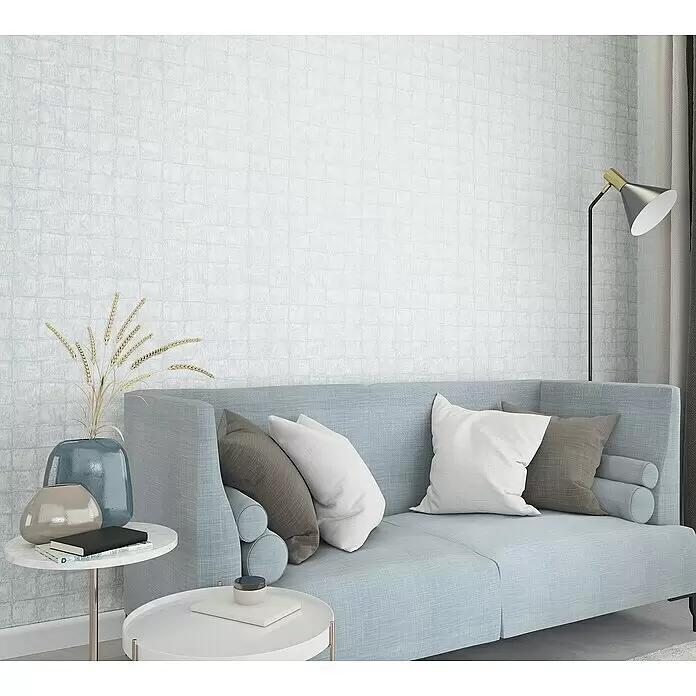 Marburg Botanica Vliestapete - Blau/Grau, Fliesenoptik, 10,05 x 0,53 m - Hellblaues Sofa mit Zierkissen in einem modernen Wohnzimmer, ergänzt durch Beistelltische und Stehlampe.