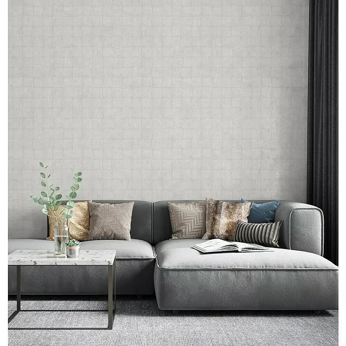 Marburg Botanica Vliestapete - Hellgrau, Fliesenoptik, 10,05 x 0,53 m - Nahaufnahme eines stilvollen grauen Sofas mit Kissen und Beistelltisch in einem modern eingerichteten Wohnzimmer mit strukturierten Wänden.