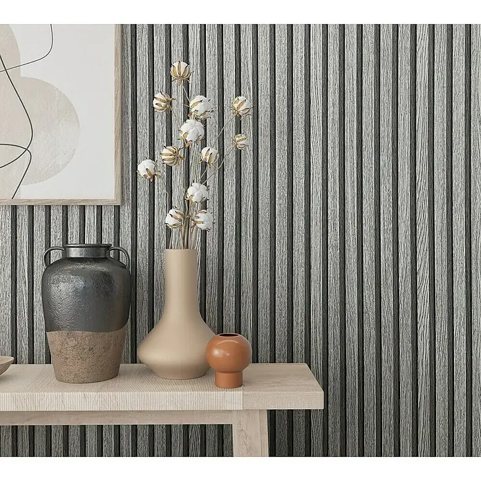 Marburg Botanica Vliestapete Wandpaneele - Grau, Holzoptik, 10,05 x 0,53 m - Deko-Arrangement mit einer grauen Vase, einem hellen Krug und einer kleinen orangen Kugel auf einem Holztisch vor einer Wand mit Holzpaneelen.