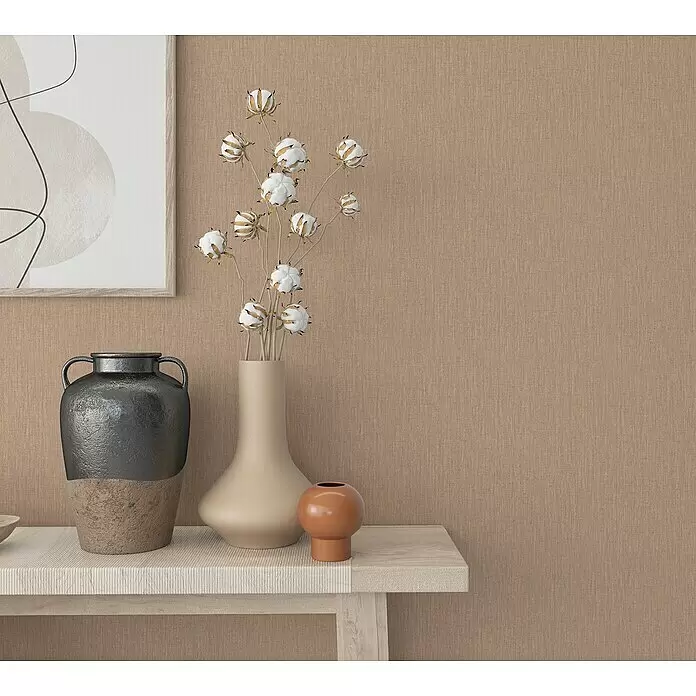 Marburg Botanica Vliestapete - Beige, Uni, 10,05 x 0,53 m - Strukturierte, warmbeige Wandverkleidung mit Deko-Vasen und Kunstwerk auf einem hellen Holztisch.