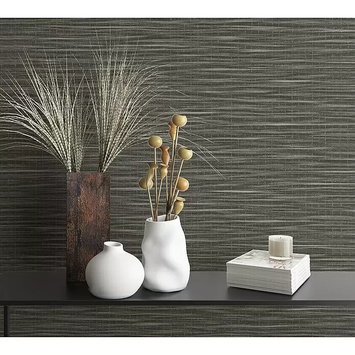 Marburg Botanica Vliestapete Webstruktur - Dunkelbraun, Uni, 10,05 x 0,53 m - Dunkler Konsolentisch mit Dekoelementen: hohes Gras in rustikaler Vase, weiße Vasen mit Holzstäben, Zeitschriften und Kerze.