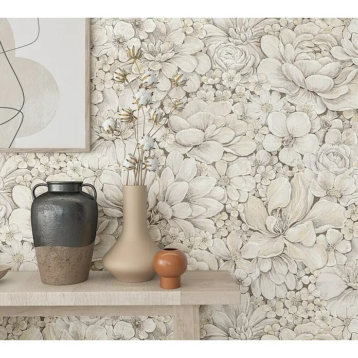 Marburg Botanica Vliestapete - Greige, Floral, 10,05 x 0,53 m - Nahaufnahme eines Zimmers mit einer Tischplatte auf der Vasen, Kunstwerke und Gegenstände aufgestellt sind, vor einer floralen Tapete.