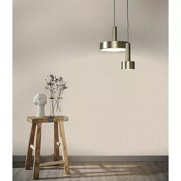 Marburg Botanica Vliestapete Struktur - Beige, Uni, 10,05 x 0,53 m - Hellbeigefarbene Tapete mit gewebter Textur an einer Wand in einem Raum, hinter einem Holzhocker und Pendelleuchten.