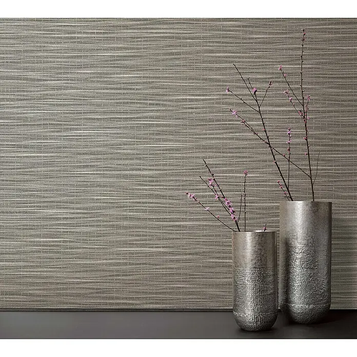 Marburg Botanica Vliestapete Webstruktur - Braun, Uni, 10,05 x 0,53 m - Zwei dekorative silberne Vasen mit zarten rosa blühenden Zweigen auf einer dunklen Oberfläche vor einer strukturierten Wand.