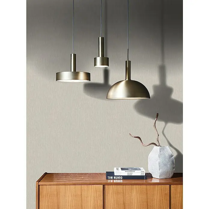 Marburg Botanica Vliestapete Struktur - Dunkelgreige, Uni, 10,05 x 0,53 m - Drei moderne Pendelleuchten aus gebürstetem Messing hängen über einem Sideboard und schaffen eine stilvolle Atmosphäre.