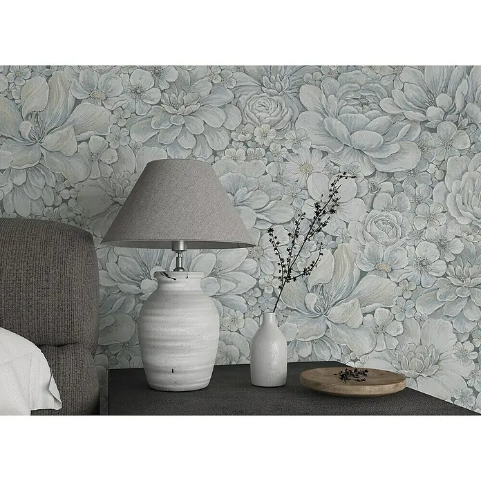 Marburg Botanica Vliestapete - Blau/Grau, Floral, 10,05 x 0,53 m - Elegante Tischleuchte mit grauem Lampenschirm und Keramikfuß, kombiniert mit einer zarten Vase und einer Holzschale auf einem Nachttisch vor floraler Tapete.
