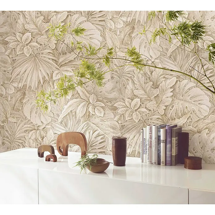 Marburg Botanica Vliestapete - Beige, Floral, 10,05 x 0,53 m - Nahaufnahme eines stilvollen Interieurs mit Büchern, Holzelefanten und Pflanzen vor einer eleganten Blättertapete.