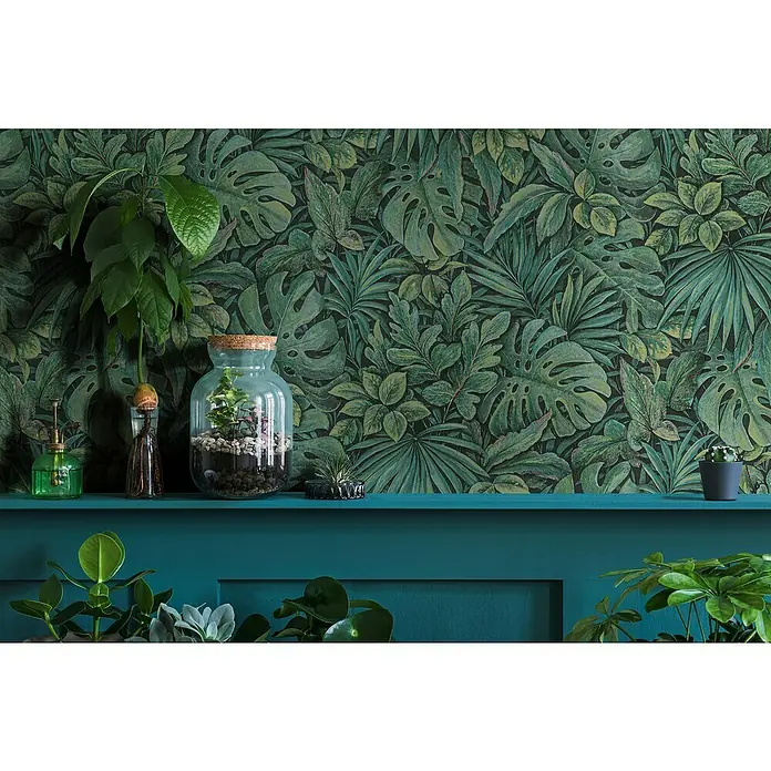 Marburg Botanica Vliestapete - Grün, Floral, 10,05 x 0,53 m - Zimmerpflanzen-Arrangement auf einem Regal vor einer grünen Blättertapete, die eine ruhige, natürliche Atmosphäre schafft.