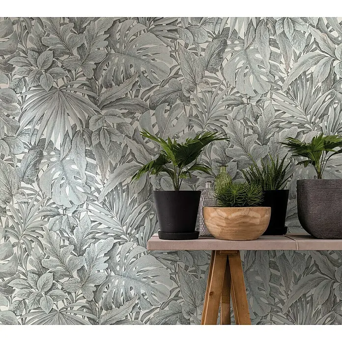 Marburg Botanica Vliestapete - Weiß/Grün, Floral, 10,05 x 0,53 m - Zimmerpflanzen in verschiedenen Töpfen stehen auf einem Tisch vor einer botanischen Tapete, die einen Hauch von Grün in den Raum bringt.