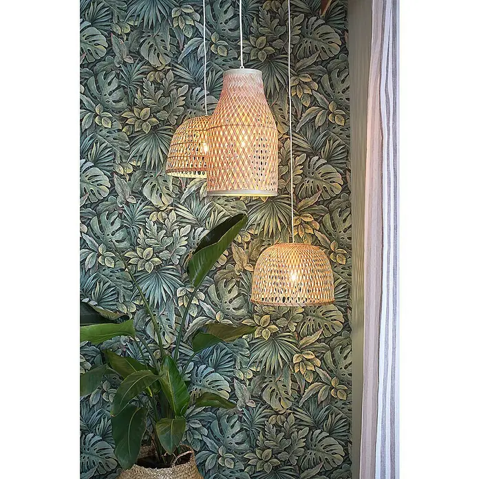 Marburg Botanica Vliestapete - Grün, Floral, 10,05 x 0,53 m - Drei hängende Lampen aus Rattan vor einer grünen Blättertapete. Die Lampen strahlen warmes Licht aus und ergänzen das natürliche Ambiente.