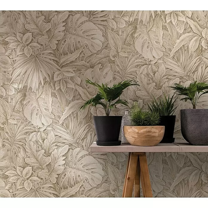 Marburg Botanica Vliestapete - Beige, Floral, 10,05 x 0,53 m - Beige Tapete mit tropischem Blattmuster an einer Wand, hinter Topfpflanzen auf einem Regal.