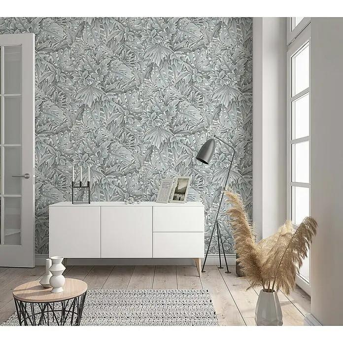 Marburg Botanica Vliestapete - Weiß/Grün, Floral, 10,05 x 0,53 m - Ein stilvolles Zimmer mit einer grauen Dschungeltapete, einer weißen Kommode, einer Stehlampe und einem Beistelltisch mit Vasen.