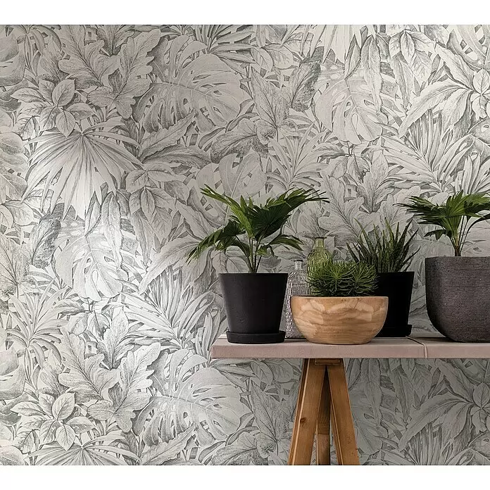 Marburg Botanica Vliestapete - Hellgrau, Floral, 10,05 x 0,53 m - Graue Tapete mit detailliertem tropischem Blättermuster, die den Raum mit Topfpflanzen auf einem Holztisch dekoriert.
