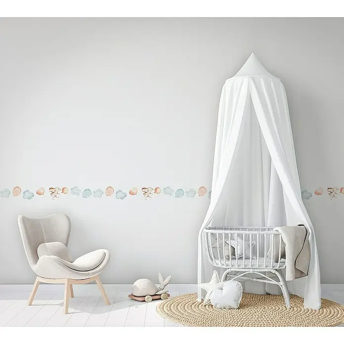 Marburg Kids' Walls Tapetenborte - Kunststoff, Weiß/Blau/Beige - Kinderzimmer mit einer Bordüre mit Hasen-, Ballon- und Wolkenmotiven, einem Sessel und einem Kinderbett mit Baldachin.
