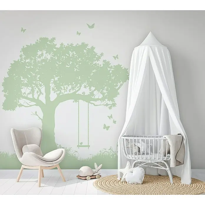 Marburg Kids' Walls Fototapete Baumschaukel - B x H: 212 x 270 cm, Vlies - Ein verträumtes Kinderzimmer mit einem weißen Babybett, einem bequemen Sessel und einer grünen Baum-Wanddekoration, die eine beruhigende Atmosphäre schafft.