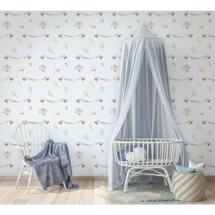 Marburg Kids' Walls Vliestapete - Grau/Multicolor, Grafisch, 10,05 x 0,53 m - Babyzimmer mit einer weißen Wiege mit Baldachin, einem Korbstuhl mit Decke und einem Korb mit Kissen auf einem Weltkarten-Teppich.