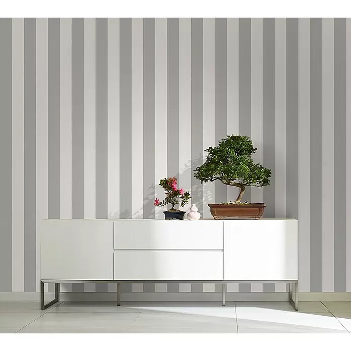 Marburg Kids' Walls Vliestapete - Grau/Weiß, Streifen, 10,05 x 0,53 m - Modernes weißes Sideboard mit minimalistischem Design und Metallbeinen, dekoriert mit zwei Bonsai-Bäumen und einer kleinen Vase.