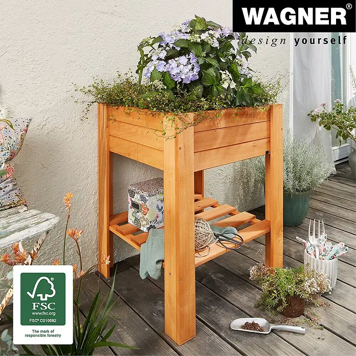 Wagner System GreenFamily Hochbeet GreenBOX light - 53,5 x 53,5 x 70 cm, Dunkelbraun - Das Bild zeigt einen erhöhten, hölzernen Pflanzkasten mit einer lila Pflanze darin. Das Beet hat ein Ablagefach mit Gartengeräten und ist für den Außenbereich geeignet.