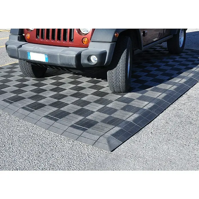 Eckelement Mixtile - Anthrazit, 20 x 20 cm, 1 Stk. - Ein roter Jeep parkt auf einem grauen, modularen Bodensystem für den Außenbereich, das auf einem Kiesweg verlegt ist.
