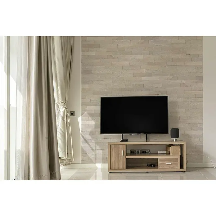 Wodewa Holzriemchen 400 Eiche Arctic - 400 x 80 mm, Stärke: 2 mm - 6 mm, 32 Stk., 1 m², Verklebung - Ein modernes Wohnzimmer mit einem großen Flachbildfernseher auf einem Holzschrank, vor einer dekorativen Steinwand. Elegante Vorhänge schmücken das Fenster.