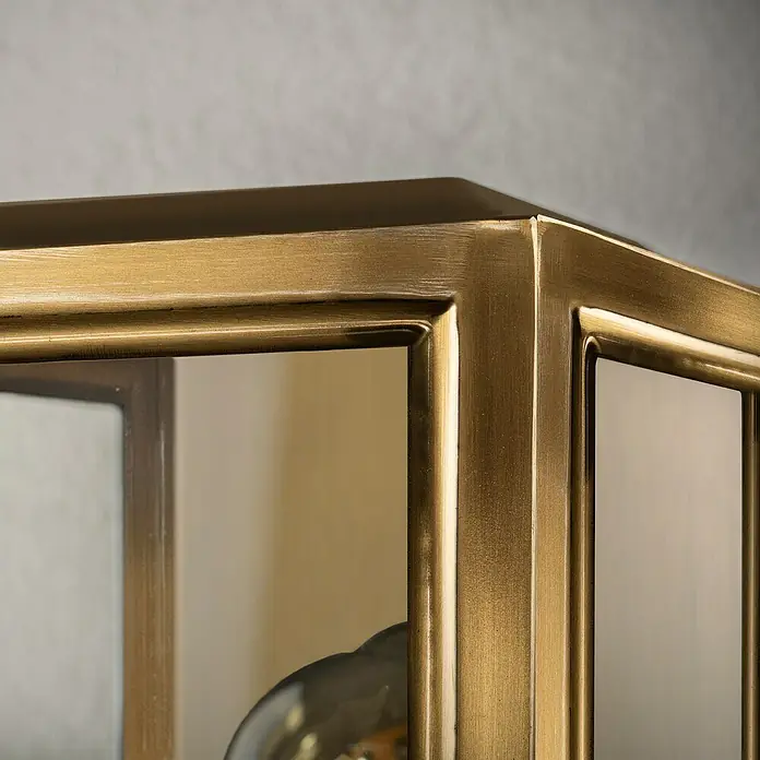 Konstsmide Außenwandleuchte Carpi - 60 W, 15 x 12,5 x 30 cm, Messing, IP44 - Detailaufnahme eines eleganten Schrankes mit Goldrahmen und Glasfront, der einen Hauch von Luxus und Raffinesse ausstrahlt.