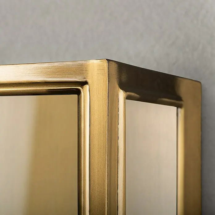 Konstsmide Außenwandleuchte Carpi - 60 W, 12,5 x 20,5 x 40 cm, Messing, IP44 - Nahaufnahme einer goldenen Metallvitrine mit rechteckigem Rahmen, die ein stilvolles und elegantes Design zeigt.
