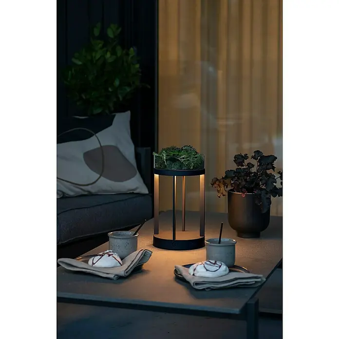 Konstsmide Außenlaterne Chieti - 17 x 17 x 25 cm, Schwarz - Elegantes Outdoor-Ambiente mit einer stilvollen Tischleuchte, die gleichzeitig als Pflanzgefäß dient, neben süßen Köstlichkeiten.