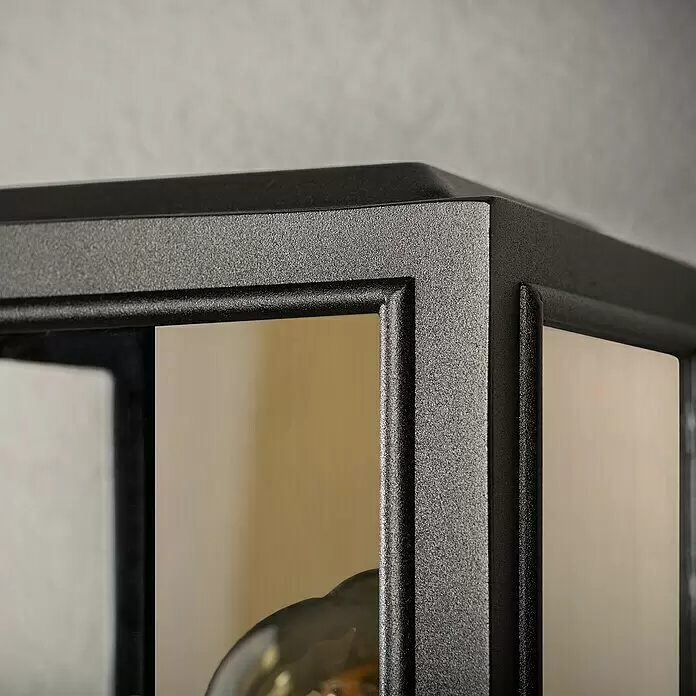 Konstsmide Außenwandleuchte Carpi - 60 W, 15 x 12,5 x 30 cm, Schwarz, Gold, IP44 - Schwarze, strukturierte Metallrahmenecke mit Glasscheiben, Teil einer Lampe oder Vitrine.