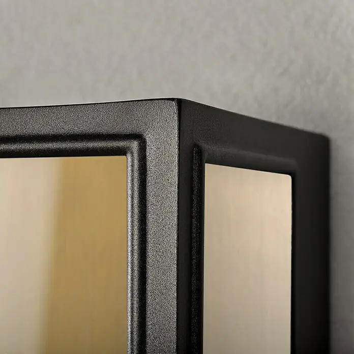 Konstsmide Außenwandleuchte Carpi - 60 W, 12,5 x 20,5 x 40 cm, Schwarz, IP44 - Detailaufnahme einer modernen, würfelförmigen Wandleuchte mit einem schwarzen Metallrahmen und warm getönten Glasscheiben.