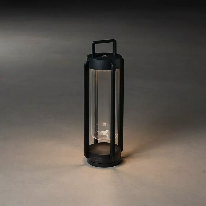 Konstsmide Außenlaterne Otranto - 15 x 15 x 44 cm, Schwarz - Elegante, tragbare Laterne mit einem schwarzen Rahmen und einem klaren Glaszylinder, die ein warmes, stimmungsvolles Licht verbreitet.