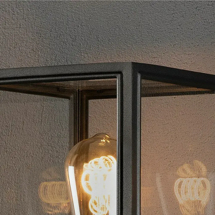 Konstsmide Außenwegeleuchte Carpi - 60 W, Farbe Gehäuse: Schwarz, 16 x 16 x 100 cm, Ohne Leuchtmittel - Nahaufnahme einer stilvollen schwarzen Außenleuchte mit einer dekorativen Glühbirne, die warmes Licht ausstrahlt.