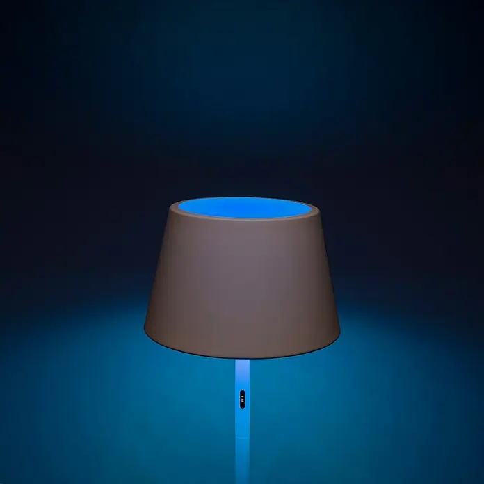 Konstsmide Außenleuchte Pomezia - Akkubetrieben, 10 W, RGBW, 35 x 35 x 150 cm, Mit Leuchtmittel, Weiß - Nahaufnahme einer Nachttischlampe mit braunem Lampenschirm und blauem Licht auf einem dunklen Hintergrund.