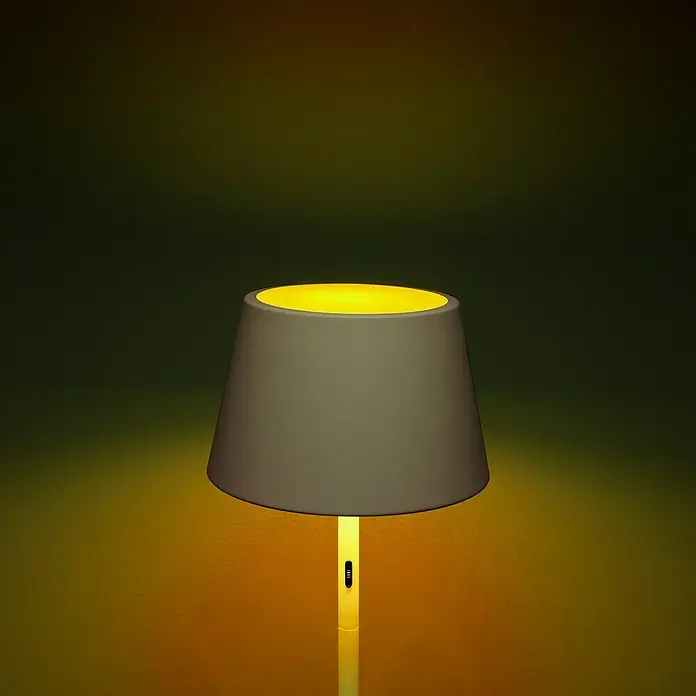 Konstsmide Außenleuchte Pomezia - Akkubetrieben, 10 W, RGBW, 35 x 35 x 150 cm, Mit Leuchtmittel, Weiß - Nahaufnahme einer modernen, stilvollen Tischlampe mit gelbem Licht und grauem Lampenschirm, die eine warme Atmosphäre erzeugt.
