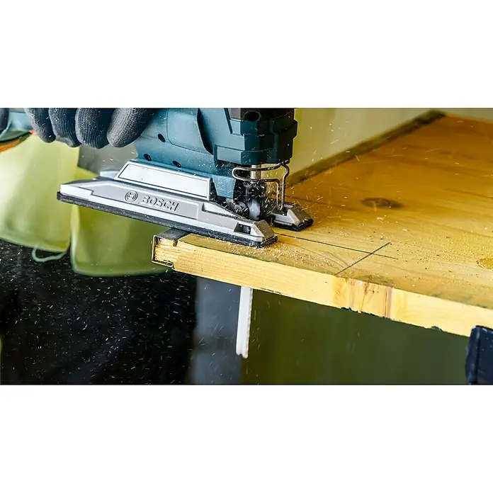 Bosch Expert Stichsägeblatt Multi Material T 367 XHM - Holz/Metall/Kunststoff, T-Schaft - Nahaufnahme einer Stichsäge von Bosch beim Schneiden eines Holzbretts, mit Sägespänen in der Luft.