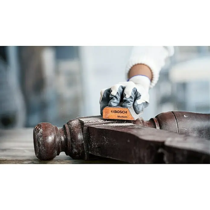 Bosch Professional Expert Schleifschwamm S473 - 120 x 98 x 13 mm, Korngröße: Sehr Fein, 1 Stk. - Ein Mann schleift ein Holzbein mit einem Bosch Schleifklotz Medium. Der Schleifklotz ist orange und hat das Bosch Logo.
