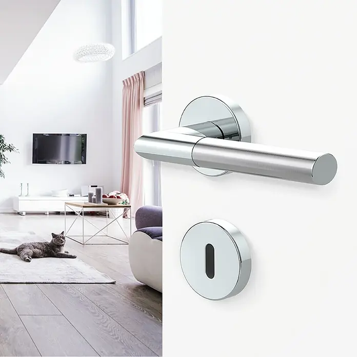 Diamond Doors Creative Drückergarnitur Dallas - Stärke Tür: 40 mm - 45 mm, Edelstahl, L-Form, Buntbart - Nahaufnahme eines eleganten Türgriffs aus Chrom, der in einem modernen Wohnraum installiert ist, mit einer Katze im Hintergrund.