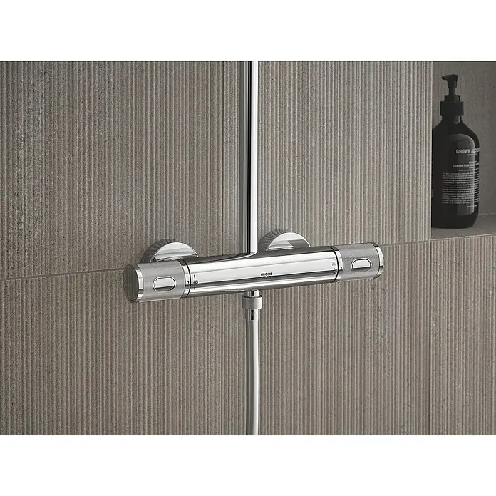 Grohe Vitalio Joy Duschsystem 260 - Mit Thermostatarmatur, Lochabstand: 100,5 cm, Anzahl Strahlarten: 3 Stk., Chrom - Nahaufnahme eines modernen Grohe Duschthermostats aus Chrom vor einer grauen, vertikal geriffelten Wand.