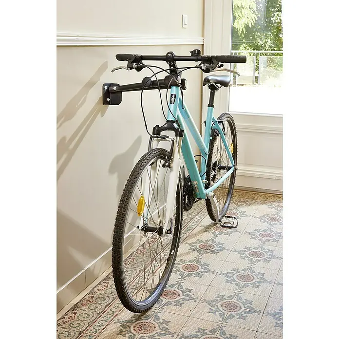Mottez Fahrrad-Wandhaken - Stahl, Schwarz - Wandhalterung mit einem hellblauen Fahrrad, das platzsparend in einem Innenraum an einer Wand befestigt ist.