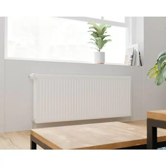 Kompaktheizkörper - B x H: 1.200 x 500 mm, Wärmeleistung bei Vorlauftemperatur von 75 °C (D: 50): 1.874 W, Typ Heizkörper: 22 - Weißer Heizkörper unter einem Fenster in einem hellen Raum installiert.