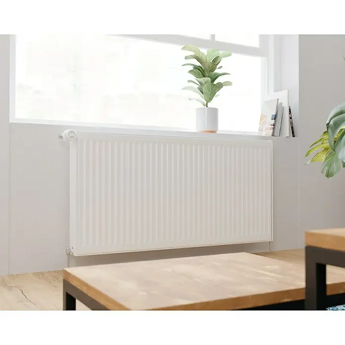 Kompaktheizkörper - B x H: 1.200 x 600 mm, Wärmeleistung bei Vorlauftemperatur von 75 °C (D: 50): 2.170 W, Typ Heizkörper: 22 - Nahaufnahme eines weißen Heizkörpers unter einem Fenster, der Wärme und Komfort in einem modernen Interieur bietet.