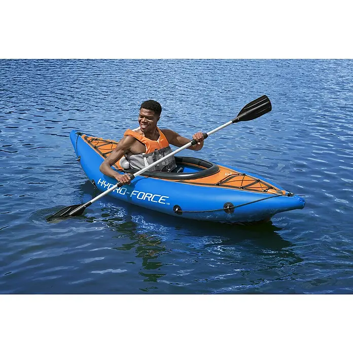 Bestway Hydro Force Kayak Cove Champion - Plástico, Azul/Naranja/Blanco - Un hombre rema en el agua en un kayak Hydro-Force azul y naranja, equipado con un remo y un chaleco salvavidas.