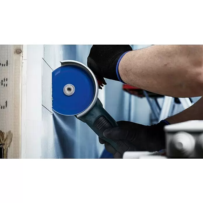 Bosch Expert Karbid-Trennscheibe Carbide Multi Wheel X-Lock - Durchmesser: 115 mm, 1 Stk. - Person in Handschuhen schneidet mit einem Winkelschleifer mit blauer Scheibe eine rechteckige Öffnung in Trockenbauwand.