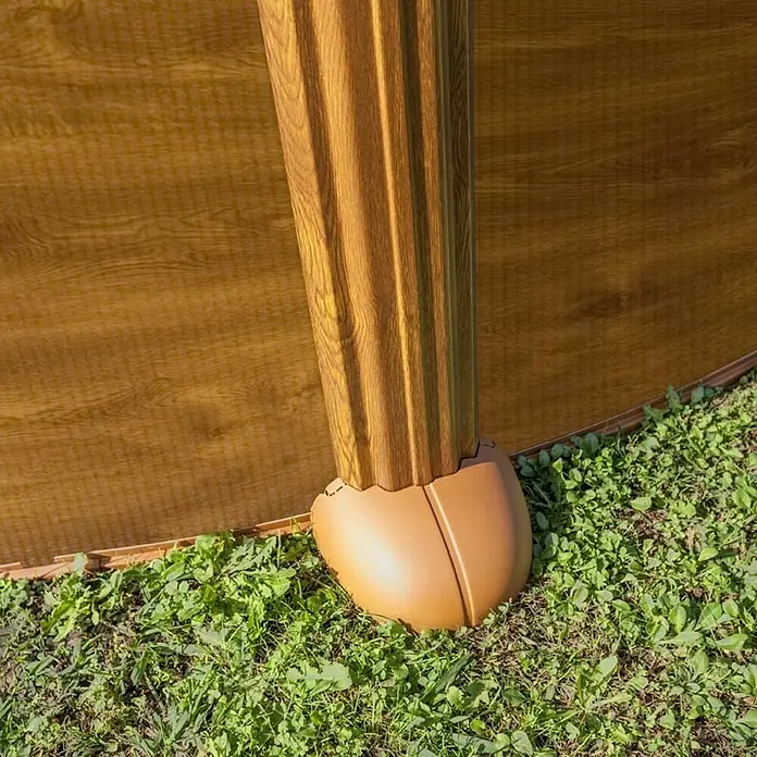 Gre Piscina de acero desmontable Mauritius - L x An x Al: 610 x 375 x 132 cm, Marrón claro, 23.281 l - Primer plano de un poste de cerca marrón con una textura de grano de madera, colocado sobre una base redondeada en medio de vegetación verde.