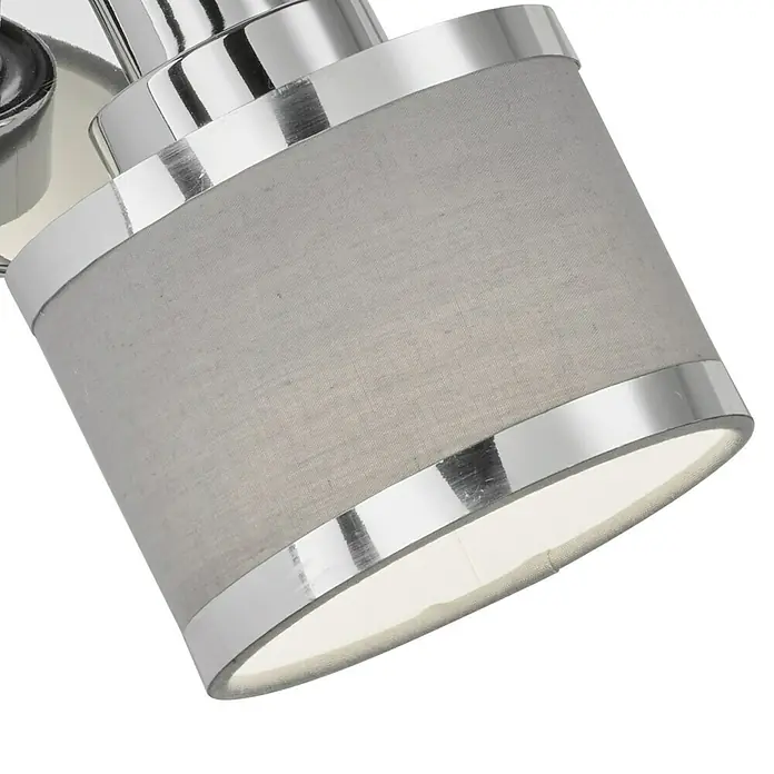 WOFI Wandstrahler Alexia - 28 W, L x B x H: 11,4 x 10 x 19 cm, Chrom, E14, 1 Stk. - Nahaufnahme einer grauen Stoff-Deckenleuchte mit silbernen Akzenten, die ein helles, nach oben gerichtetes Licht ausstrahlt.