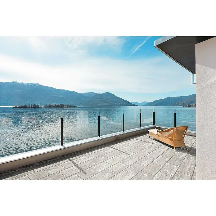 Terrassenplatte Latina - 48 x 24 x 3 cm, Pietra Luna, Beton - Einladender Balkon mit eleganten Glasgeländern und bequemer Rattanliege, der einen atemberaubenden Blick auf den See und die Berge bietet.