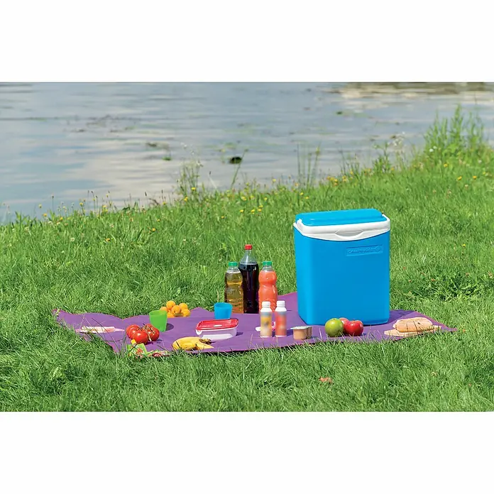 Campingaz Nevera de camping Icetime Plus - L x An x Al: 29 x 18 x 39 cm, Azul - Escena de picnic con una nevera portátil sobre una manta morada, rodeada de comida y bebida, con un lago de fondo.