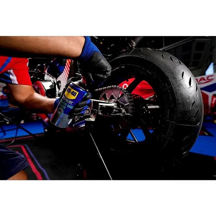 WD-40 Specialist Motorbike Aceite para cadena - 400 ml - Persona rociando WD-40 Specialist Chain Lube en una cadena de motocicleta, ayudando a mejorar el rendimiento y prolongar la vida útil.