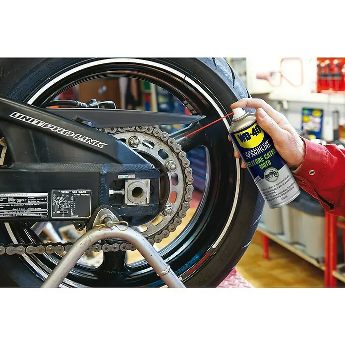 WD-40 Specialist Motorbike Limpiador de cadenas - 400 ml - Se está aplicando el limpiador de cadenas WD-40 Specialist Moto a una cadena de motocicleta para su limpieza y mantenimiento.\n