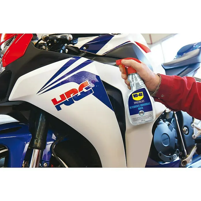 WD-40 Specialist Limpiador Total - 500 ml - Un hombre limpia una moto con WD-40 Limpiador Universal Moto. El producto promete una rápida eliminación de suciedad.
