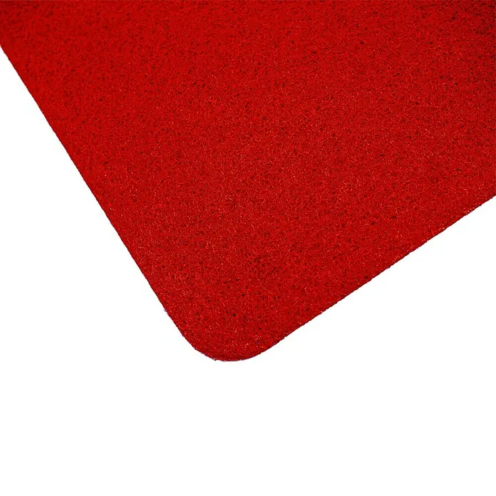 Moqueta a metros Convención Ferial - Ancho: 200 cm, 100% Polipropileno, Rojo - Primer plano de una alfombra roja texturizada, ideal como felpudo o para otros propósitos decorativos, con una esquina redondeada sobre fondo negro.